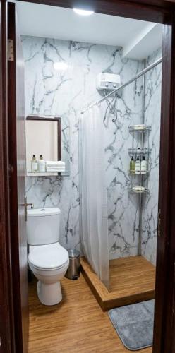a bathroom with a toilet and a marble wall at M Residence in Accra