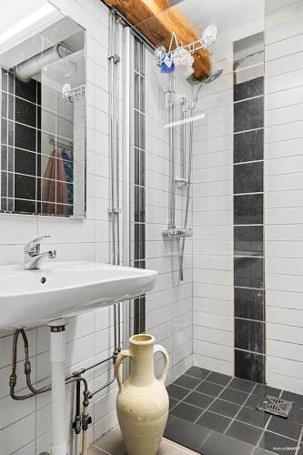 a bathroom with a sink and a vase on the floor at Klockargården Örja byväg 17 in Landskrona