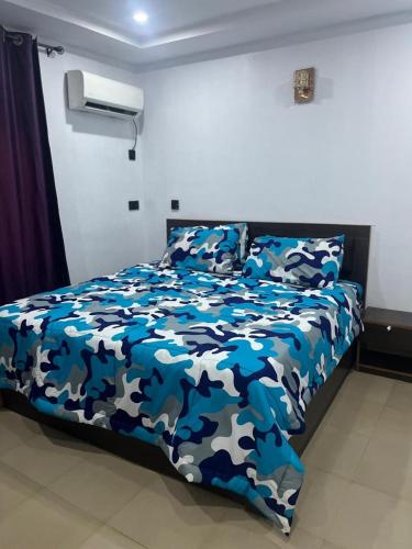 a bedroom with a bed with a blue and white comforter at House One Apartment in Akure