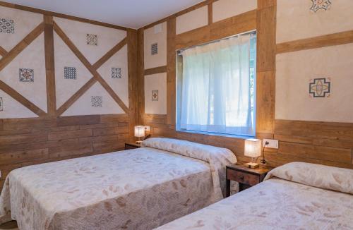 a bedroom with two beds and a window and two lamps at La Casita de Lucia in Trescasas