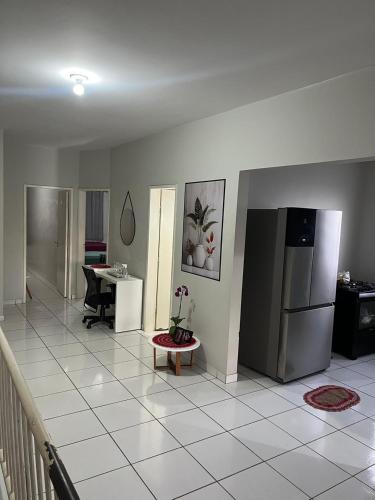 a living room with a refrigerator and a table at Quarto para viajantes in Montes Claros