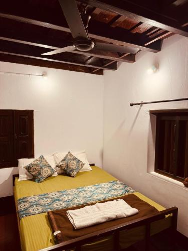 a bedroom with a bed with a yellow blanket and a ceiling at Padmalayam Heritage Villa in Mānantoddy