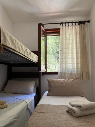 two beds in a room with a window at Splendida villetta Kal'e Moru in Marongiu