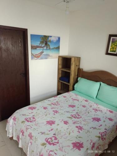 a bedroom with a bed with a floral bedspread at Recanto Mosaico in São Sebastião