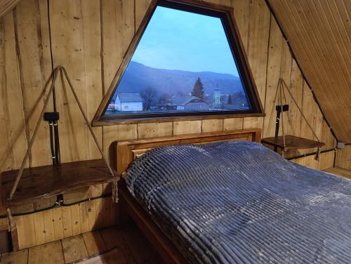 a bedroom with a large window in a wooden cabin at Мисливський Дворик in Solochyn
