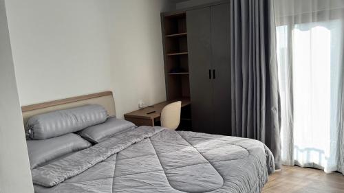 a bedroom with a bed and a desk and a window at Azure Suite Apartment - AOSIS in Bagam