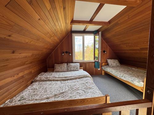 two beds in a room with wooden walls at Hygge Pržno in Pržno