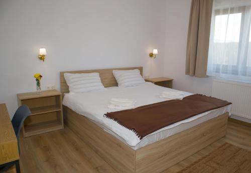 a bedroom with a bed with white sheets and a window at 4 Fa Apartmanok in Miercurea-Ciuc
