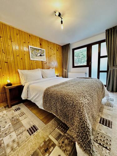 a bedroom with a large bed and wooden walls at Casa Rogin in Buhalniţa
