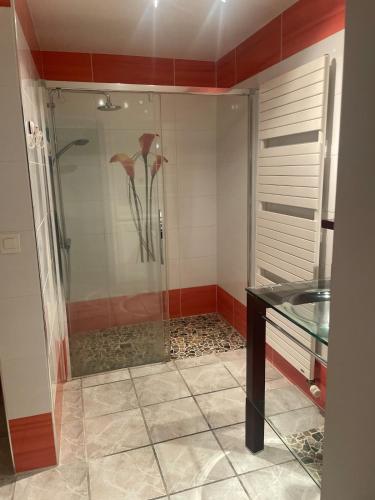 a shower with a glass door with flowers in it at Appartement calme et serein in Vals-près-le-Puy