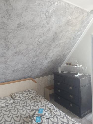 a bedroom with a bed and a dresser and a stone wall at 'Белый дом' in Balqash