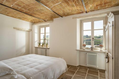 a bedroom with a white bed and two windows at Casa di Sofia in Calosso