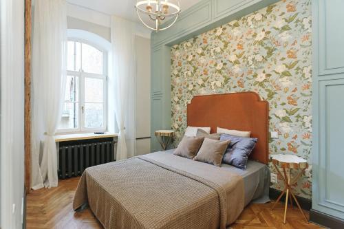 a bedroom with a bed with a floral wall at Riga Old Town Jāņa Sēta Residence in Rīga