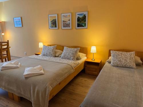 two beds in a room with two lamps and pictures on the wall at Quota 850 in Tatranská Lomnica