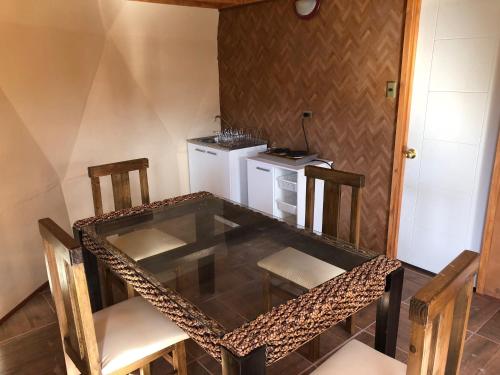 a glass table and chairs in a room with a kitchen at Hotel Observatorio TukunMapu in Vicuña