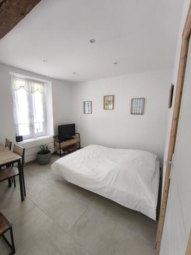 a white bedroom with a bed and a table at la longère du moulin in Noyers-sur-Cher