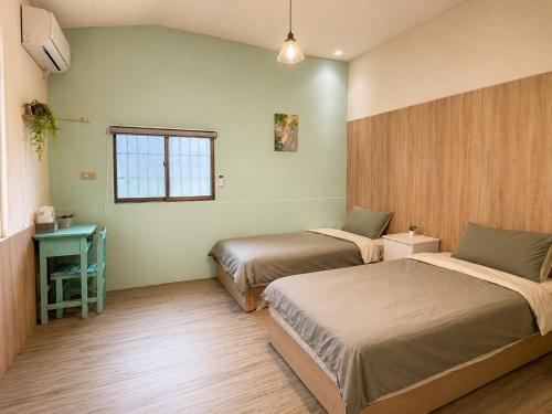 a bedroom with two beds and a window at 巷弄內的老宅27 in Pingtung City