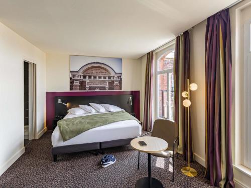 a hotel room with a bed and a table at Mercure Lille Roubaix Grand Hôtel in Roubaix