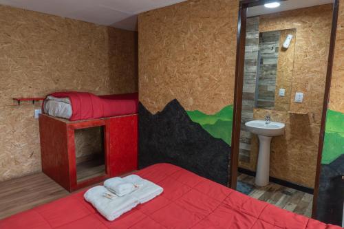 a bedroom with a red bed and a sink at Moving Hostel Travel Bar in San Carlos de Bariloche