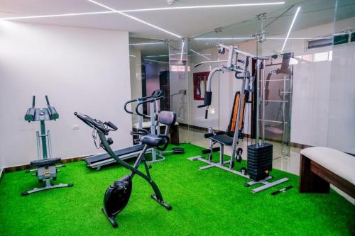 a room with green carpet and a gym with exercise equipment at BRITNEY HOTEL Machala in Machala