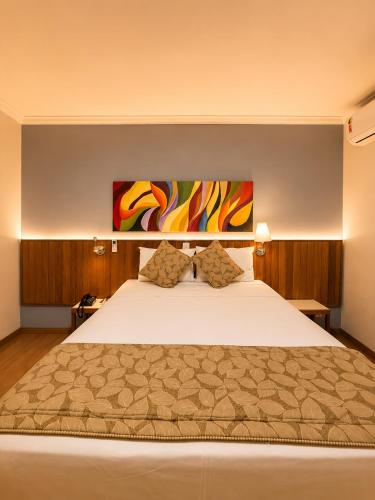 ein Schlafzimmer mit einem großen Bett und einem Gemälde an der Wand in der Unterkunft Hotel Riviera Lins in Lins