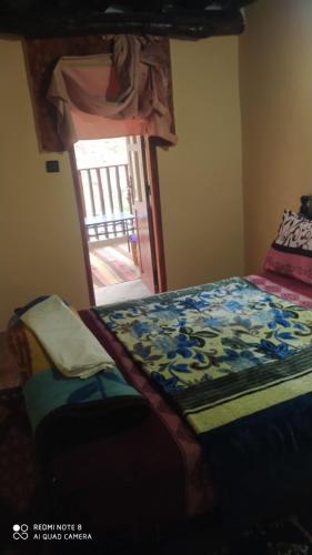 a bedroom with a bed and a door to a patio at Imlil agarssiwal in Aguersioual