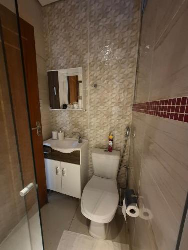 a bathroom with a white toilet and a sink at Flat Região Central 2 in Barbacena
