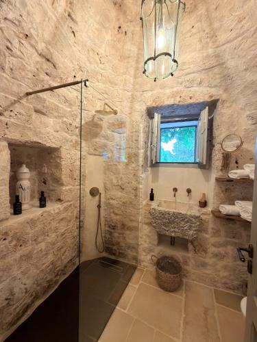 a stone bathroom with a shower and a sink at Dimora Dei Semplici in Ostuni