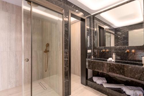 a bathroom with a glass shower and a sink at Kallos of Mykonos in Ornos