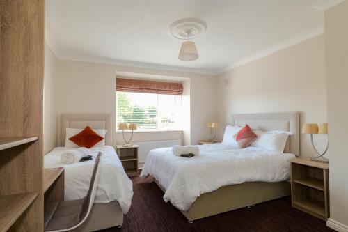 a white bedroom with two beds and a window at Almara Guesthouse in Galway