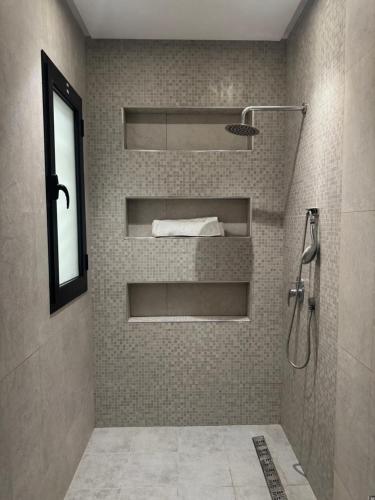 a bathroom with a shower with shelves and a sink at Pearl Beach Apartment in Monastir