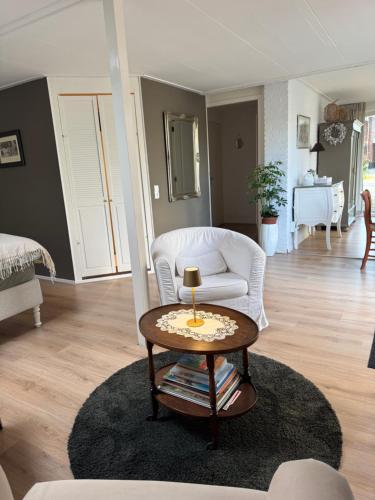 a living room with a white chair and a table at De kleine Bongerd -The little Orchard in Hengelo