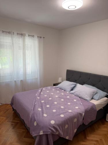 a bedroom with a bed with a purple comforter at Apartman Kata in Šmrika
