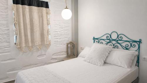 a white bedroom with a bed with a blue headboard at Est 1852 Andros - Tower 1 in Lámira