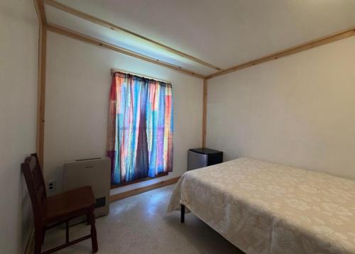 a bedroom with a bed and a chair and a window at Leapin leanas in Monson