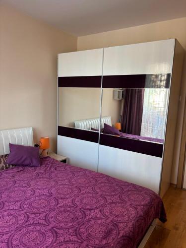 a bedroom with a purple bed and a mirror at Messembria Palace Bulgaria in Sunny Beach