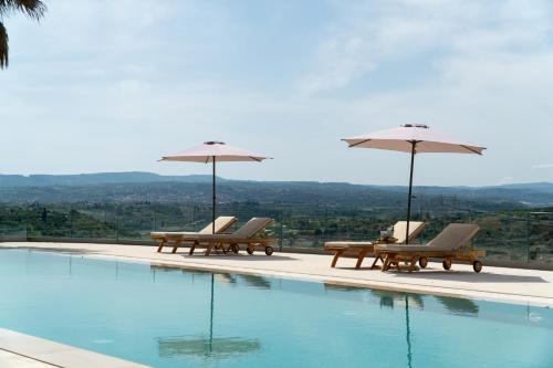 a swimming pool with two chairs and umbrellas at Tenuta Madre Vita in Syracuse