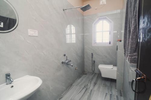 a white bathroom with a sink and a toilet at Mong Mao Manor in Guwahati