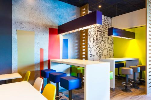 a colorful restaurant with tables and blue stools at Ibis Budget Mulhouse Centre Gare in Mulhouse