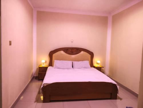 a bedroom with a bed with two lamps on two tables at Maisonnette KF Golf-Self Catering Apartments in Lubumbashi