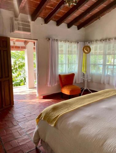a bedroom with a bed and a chair and windows at La Calita de Teques in Tequesquitengo