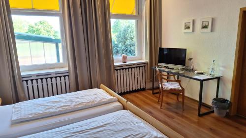 a hotel room with a bed and a desk with a television at Hotel Restaurant Zur Eisernen Hand in Viersen