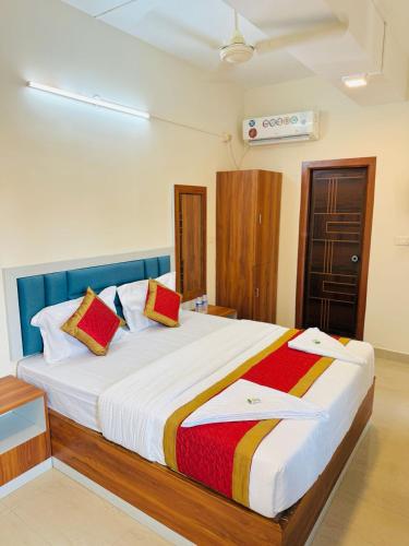a bedroom with a large white bed with colorful pillows at Hotel SAI GRAND in Mangalore