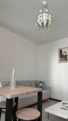 a dining room table with a couch and a chandelier at appartement de 45 m sur cour centre ville de morez in Morez