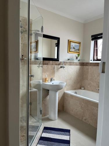 a bathroom with a sink and a bath tub at Indigo Nest in Edgemead