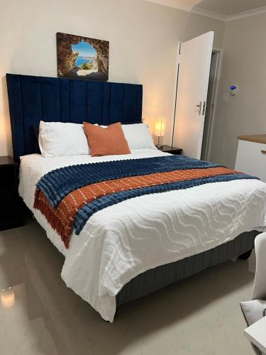 a large bed with a blue headboard in a room at Indigo Nest in Edgemead