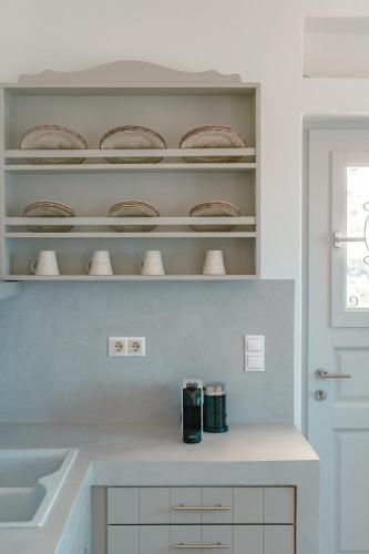 a kitchen with a counter with plates on shelves at Sea and Sun l in Mylopotas