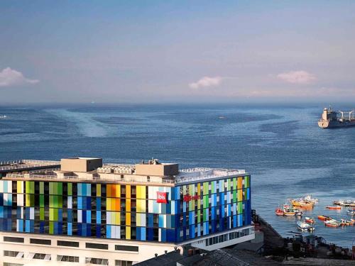 a building with a colorful facade next to the ocean at ibis Valparaiso in Valparaíso