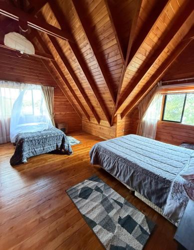 a bedroom with two beds and a wooden ceiling at Casa Costanera in Panguipulli