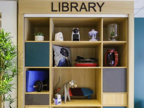 a wooden book shelf with a library in a room at Aparthotel Adagio Access Toulouse St Cyprien in Toulouse